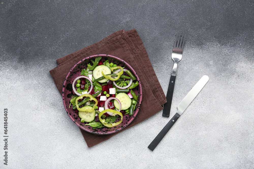 Bowl of fresh vegetable salad with beet on grey background