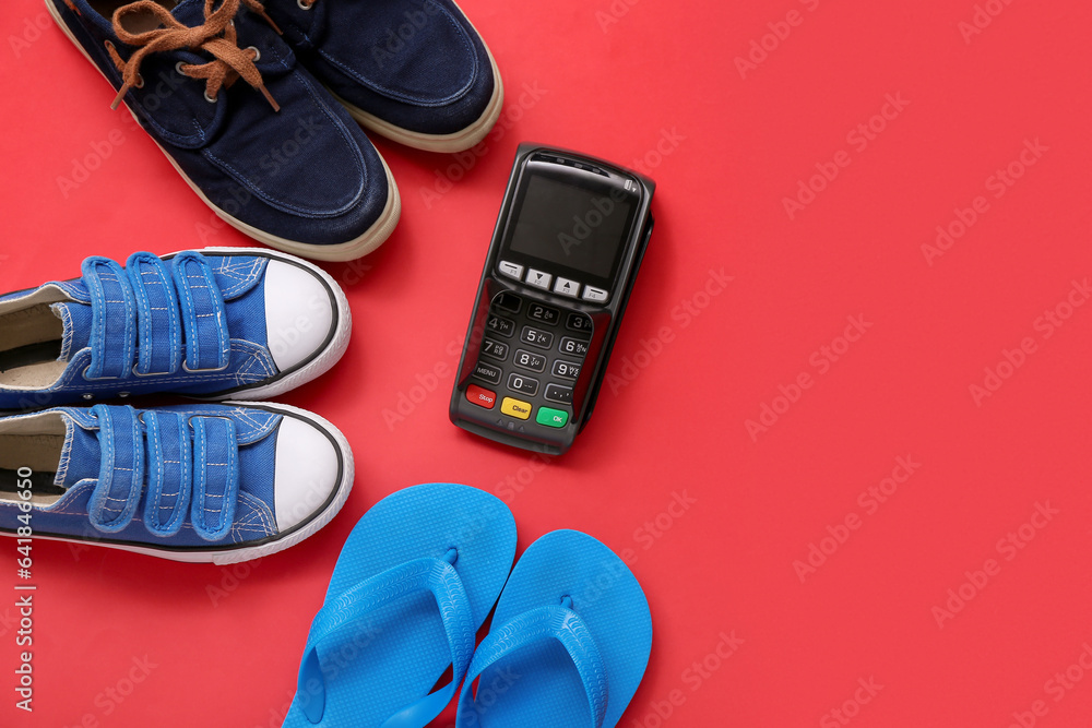 Set of stylish childs shoes and payment terminal on red background