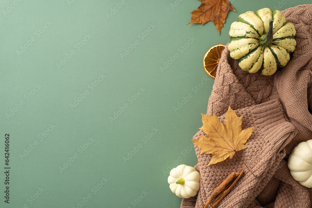 Embrace autumns coziness. Top view of rustic brown sweater, raw pattypans, cinnamon, maple leaves, 