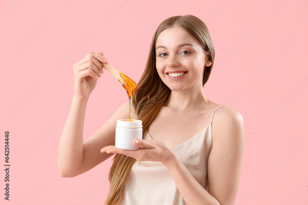 Pretty young woman with sugaring paste on pink background