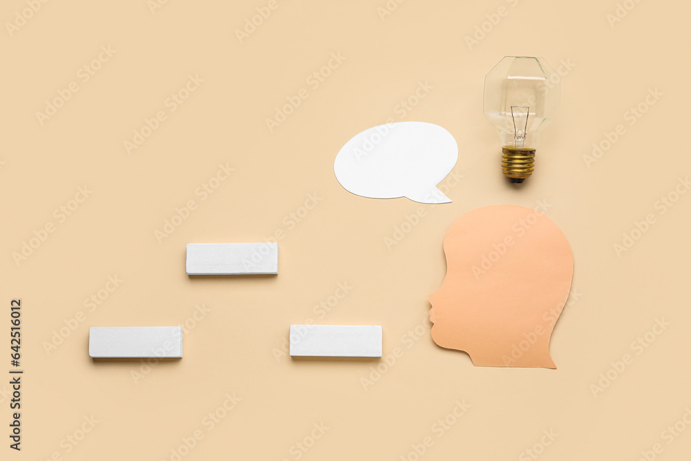 Paper human head with speech bubble, light bulb and blocks on beige background. Logic concept