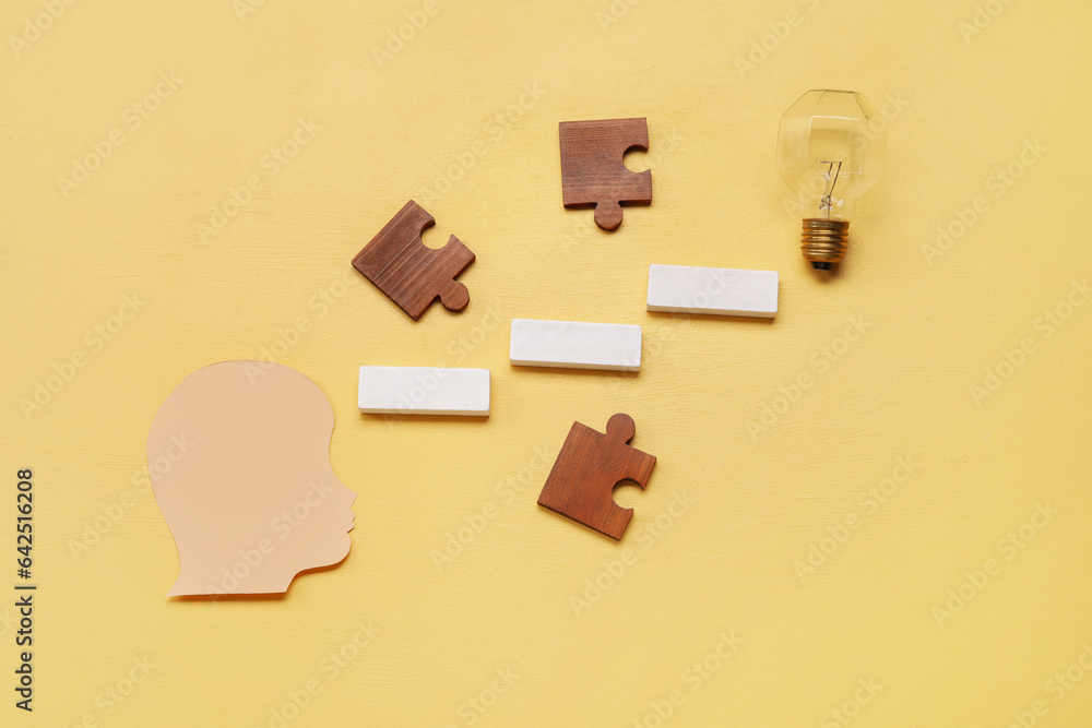 Paper human head with blocks, puzzle pieces and light bulb on yellow background. Logic concept