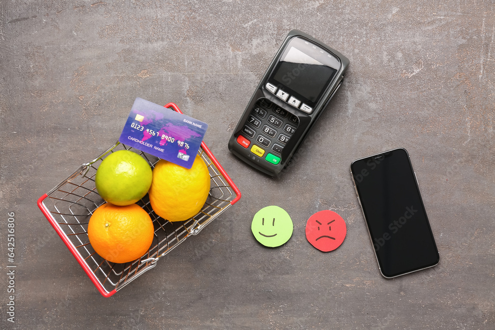 Rating smiles, shopping cart with fruits, payment terminal and mobile phone on dark background. Cust