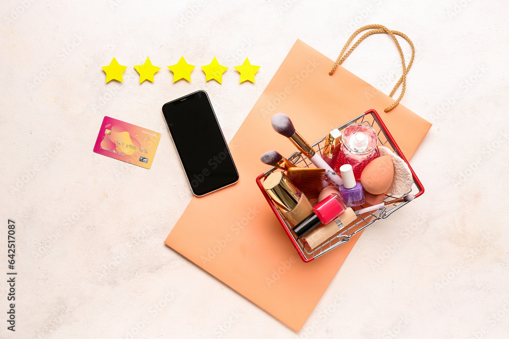 Five stars, credit card, mobile phone, bag and shopping basket with makeup products on light backgro