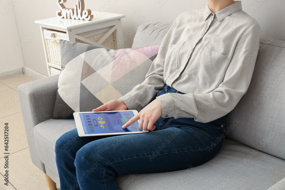 Woman with tablet computer taking experience survey on sofa at home, closeup