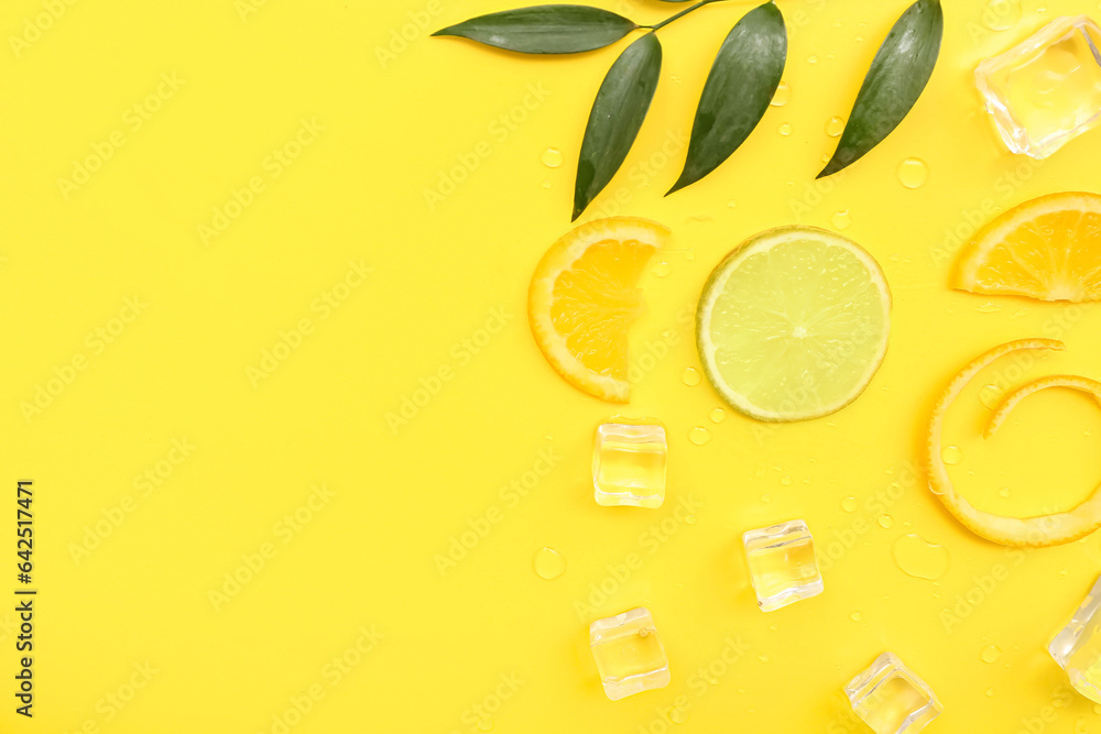 Citrus slices with ice cubes, water drops and plant branch on yellow background