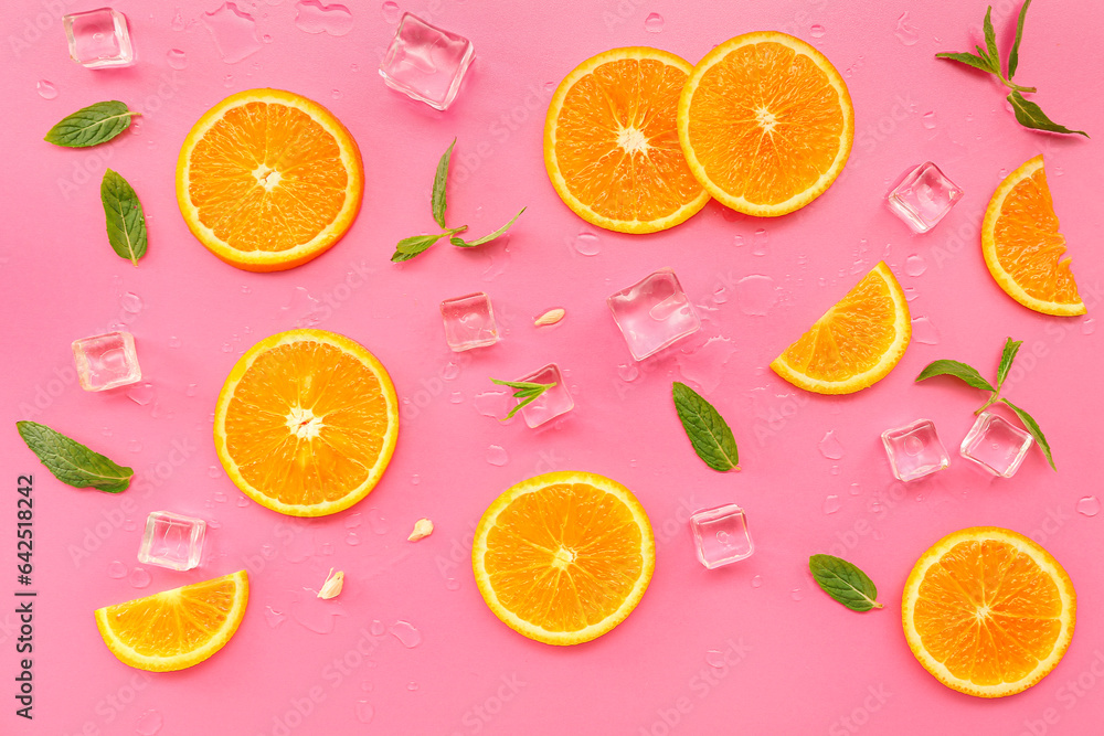 Orange slices with water drops, mint and ice cubes on pink background