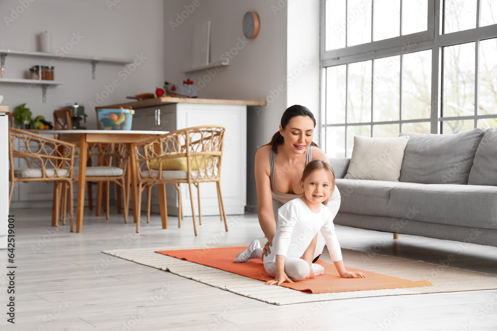 Sporty young woman with her little daughter training at home