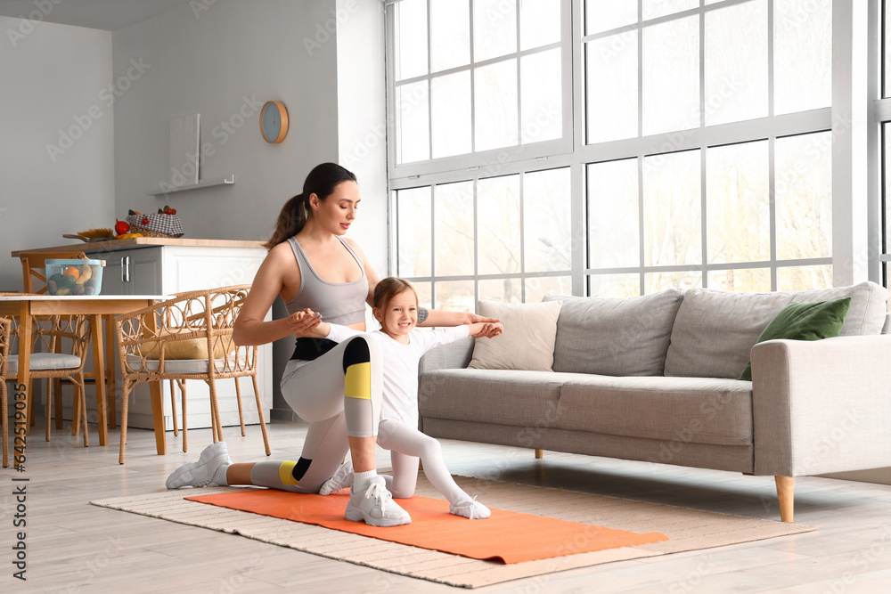 Sporty young woman with her little daughter training at home