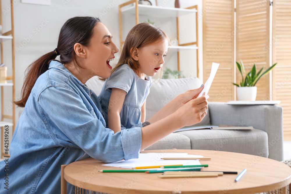 Young woman with her little daughter drawing at home