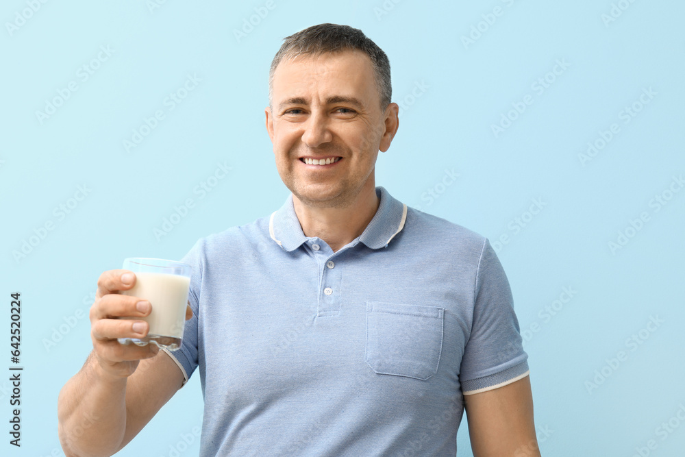 Mature man with glass of milk on blue background