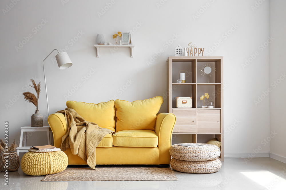 Interior of light living room with stylish yellow sofa and soft poufs