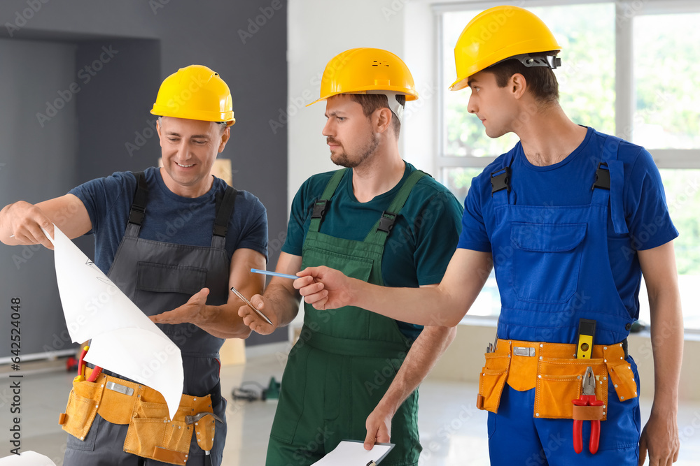 Team of male builders working with house plan in room