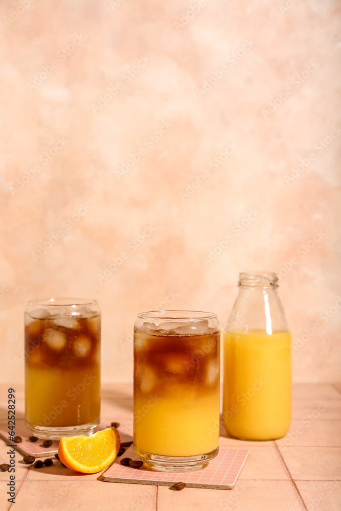 Glasses of tasty orange espresso and bottle with juice on table