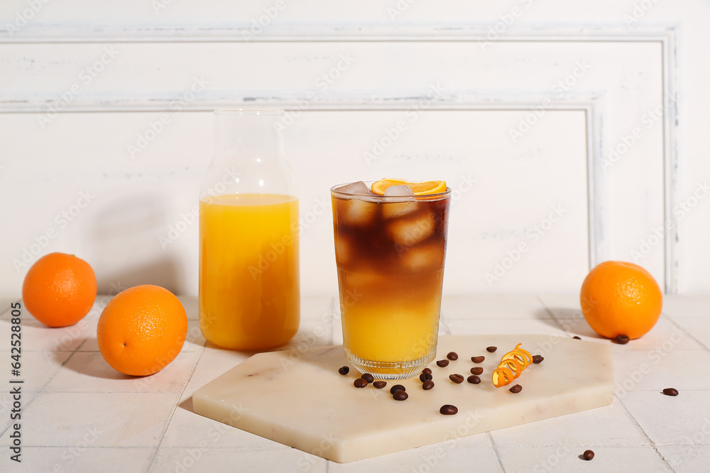 Glass of tasty orange espresso and bottle with juice on table