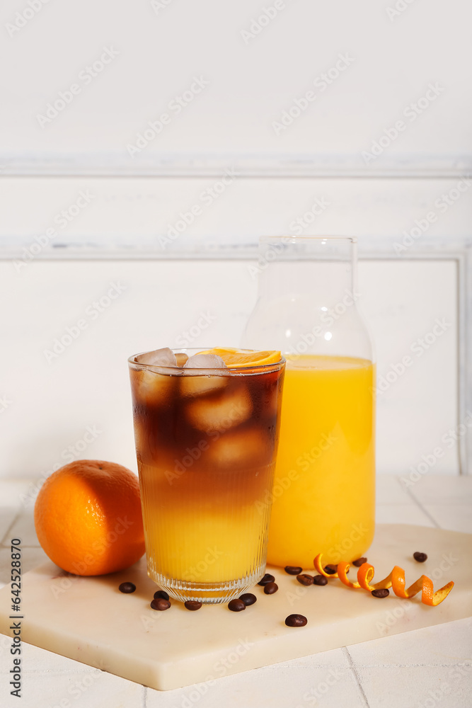 Glass of tasty orange espresso and bottle with juice on table