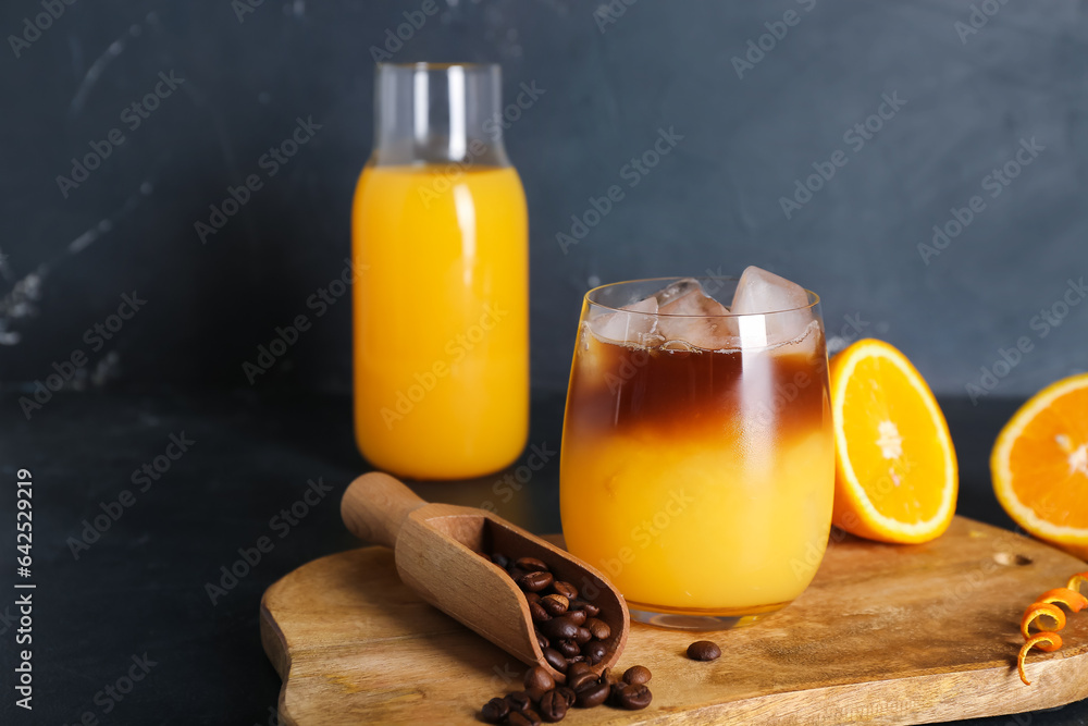 Glass of cold orange espresso on black background