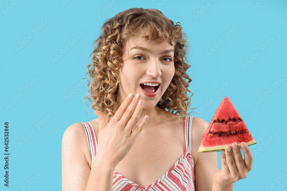 Surprised beautiful young woman with slice of fresh watermelon on blue background