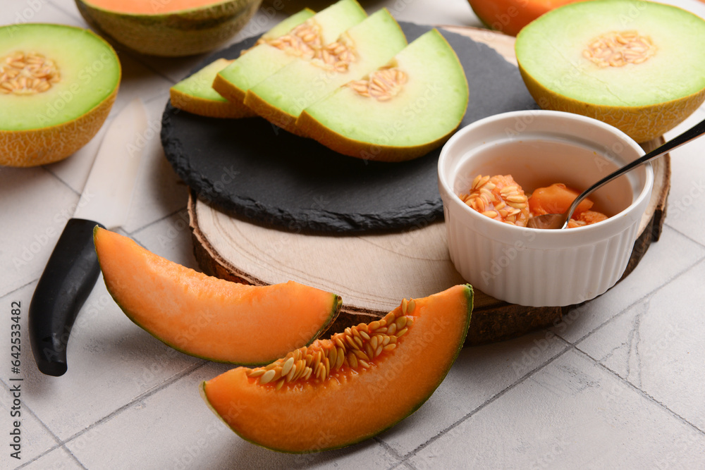 Boards with tasty ripe melons on white tile background