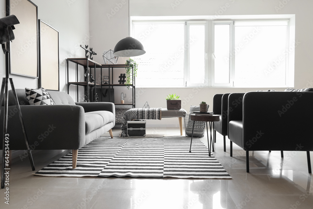 Interior of modern living room with soft bench, sofa and armchairs