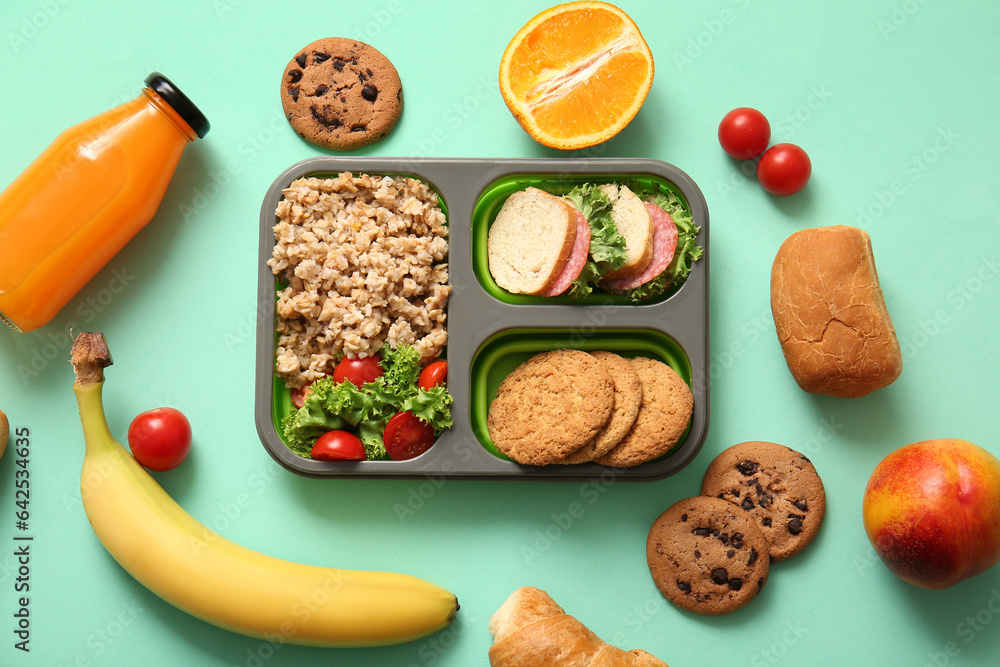 Lunchbox with delicious food and bottle of juice on turquoise background