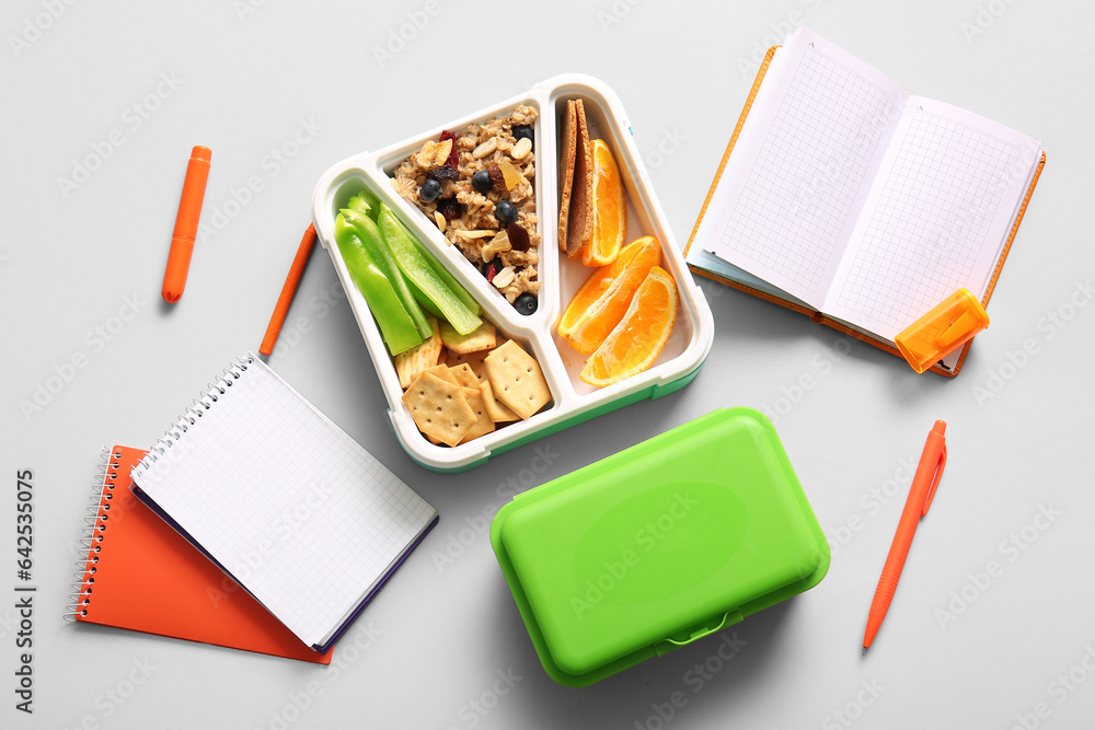 Lunchboxes with delicious food and different stationery on white background