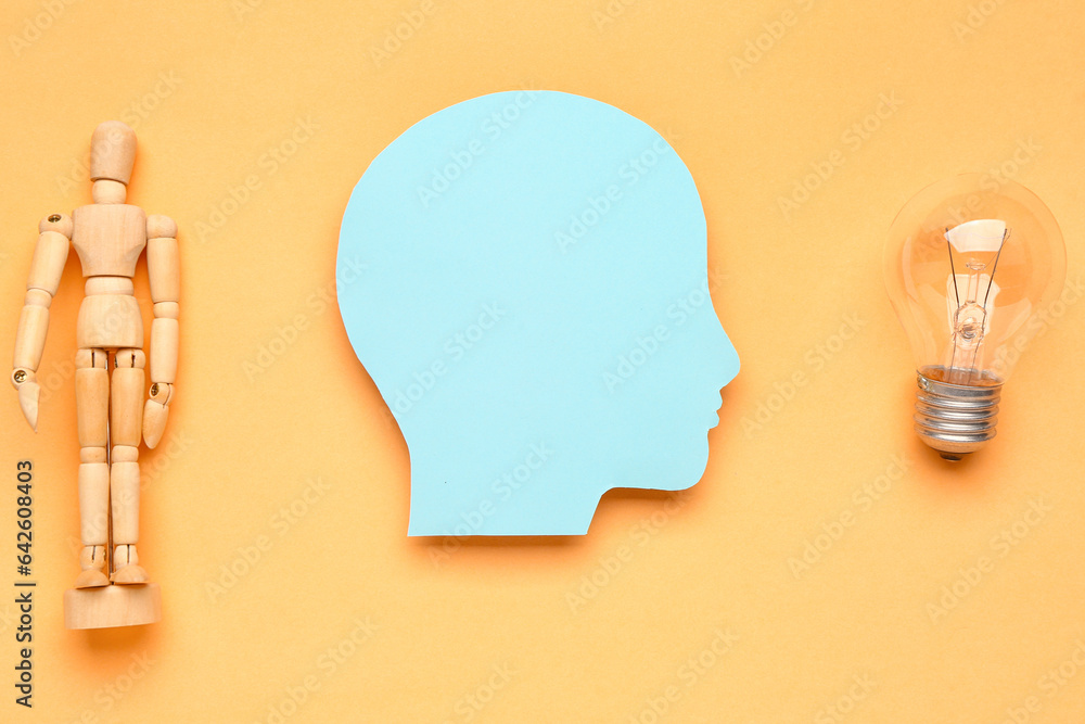 Paper human head with light bulb and wooden mannequin on color background. Logic concept