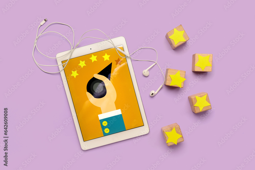 Cubes with five stars, tablet computer and earphones on lilac background. Customer experience concep