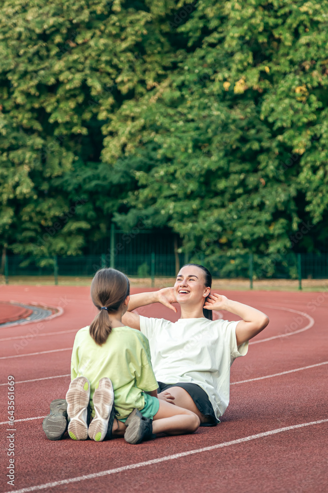 Mother and daughter go in for sports outdoors at the stadium.