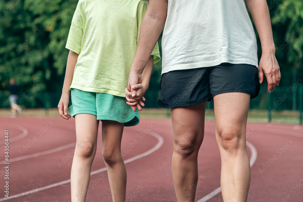 Mom and daughter hold each others hands in the stadium.