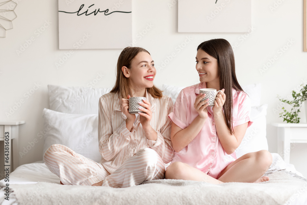 Female friends drinking coffee in bedroom