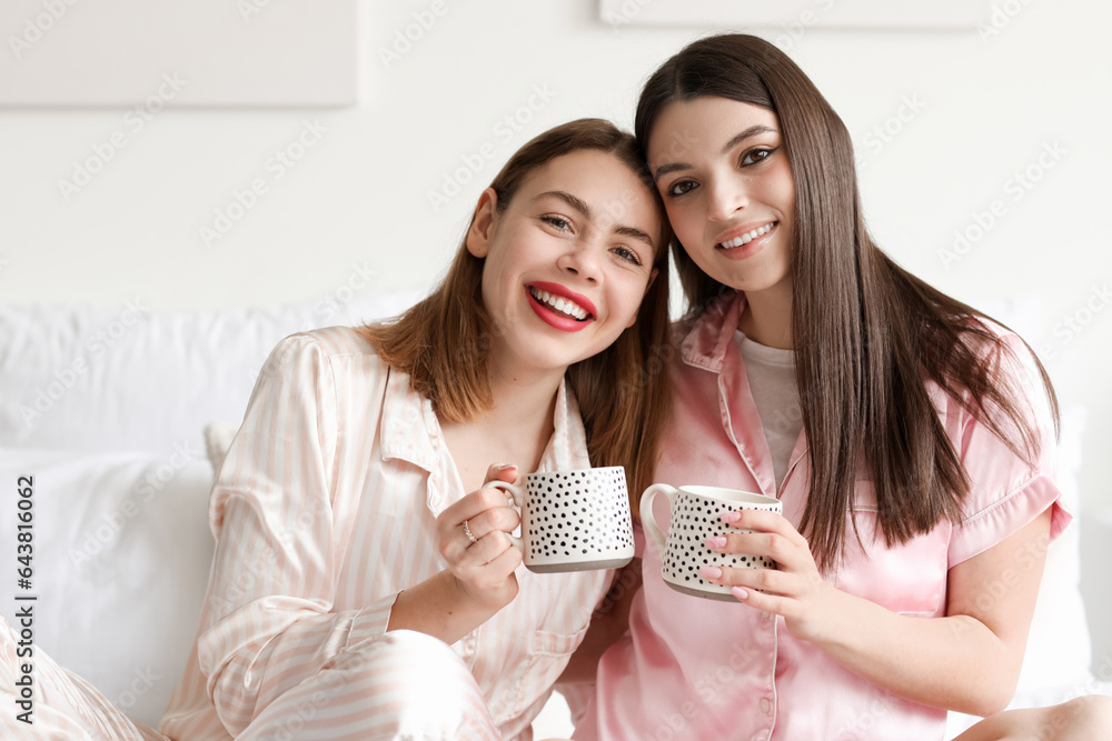 Female friends drinking coffee in bedroom