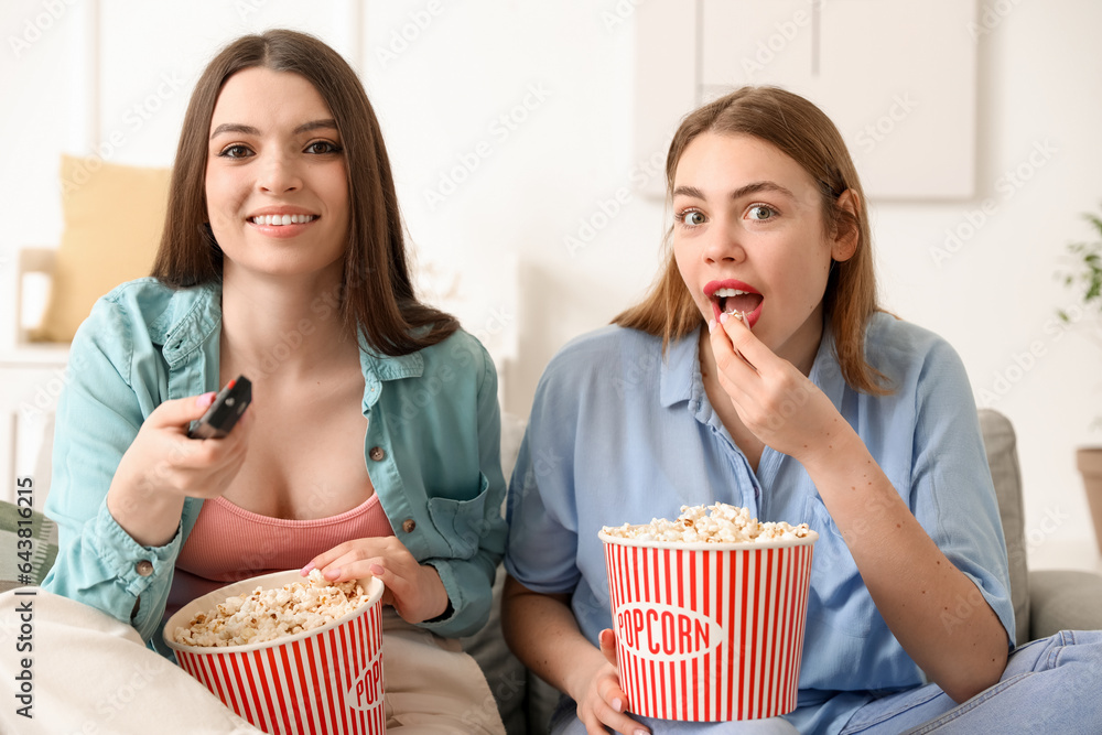 Female friends eating popcorn on sofa at home