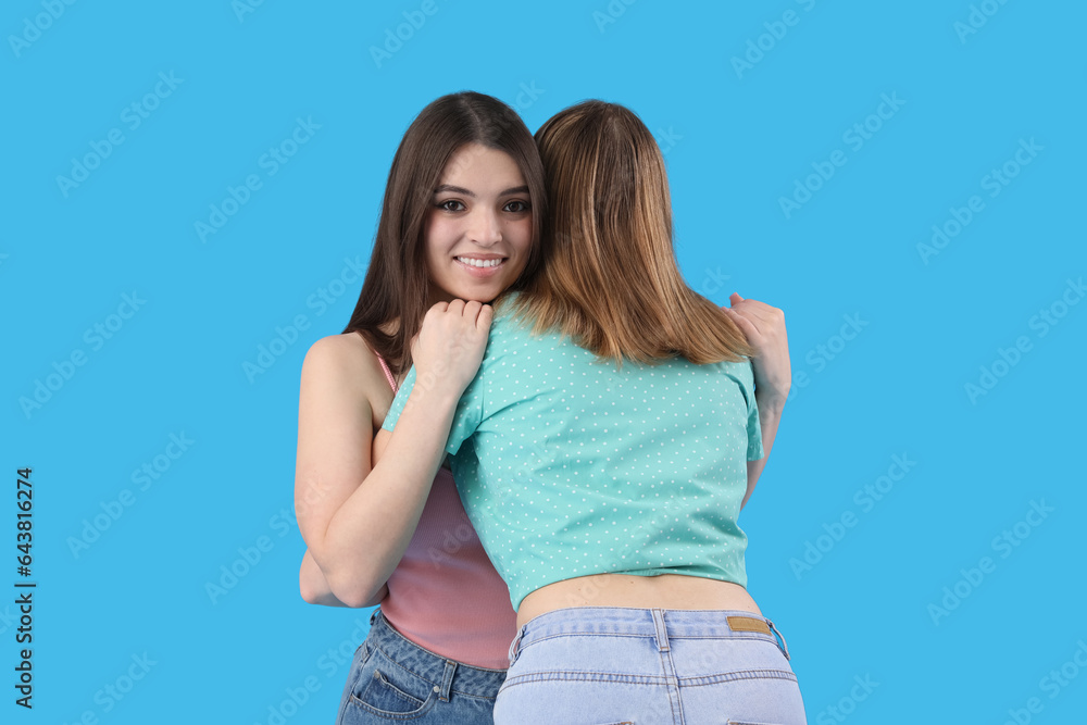 Female friends hugging on blue background