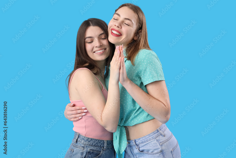 Female friends hugging on blue background