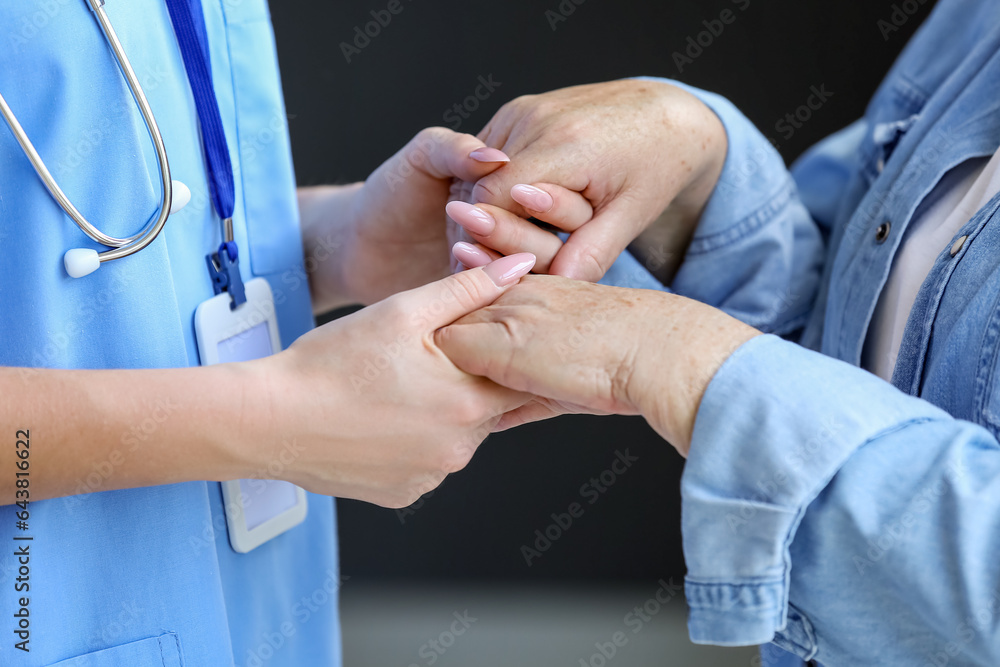 Female caregiver with senior woman holding hands, closeup