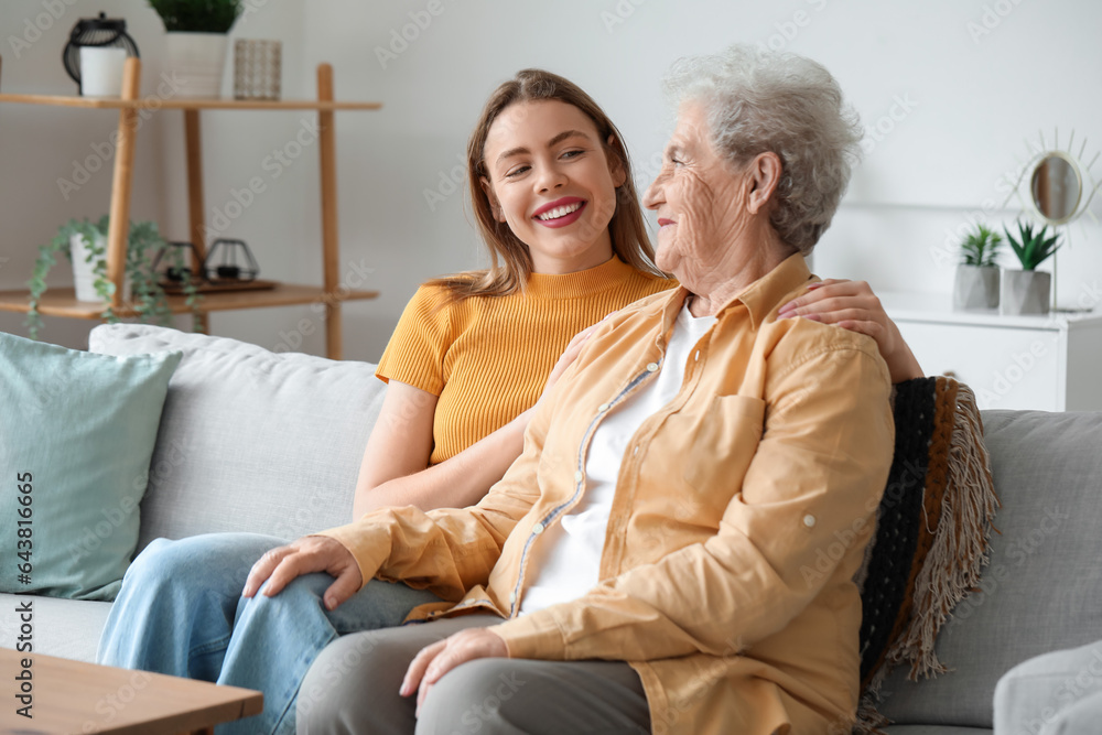 Young woman with her grandmother sitting on sofa at home