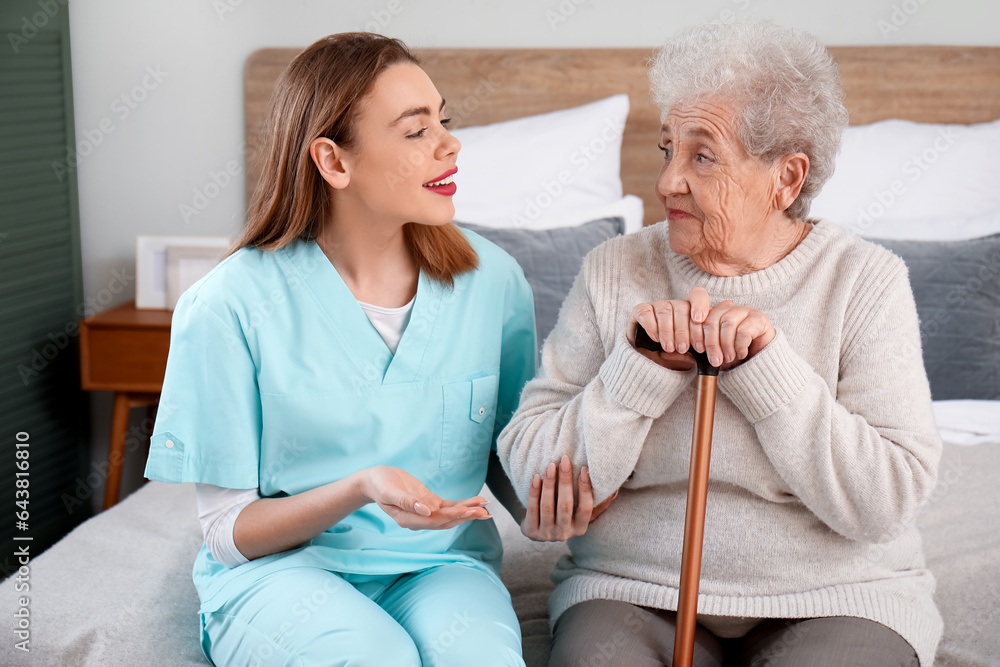 Female caregiver with senior woman in bedroom