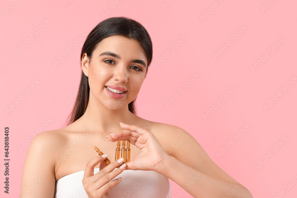 Beautiful young woman with ampules on pink background