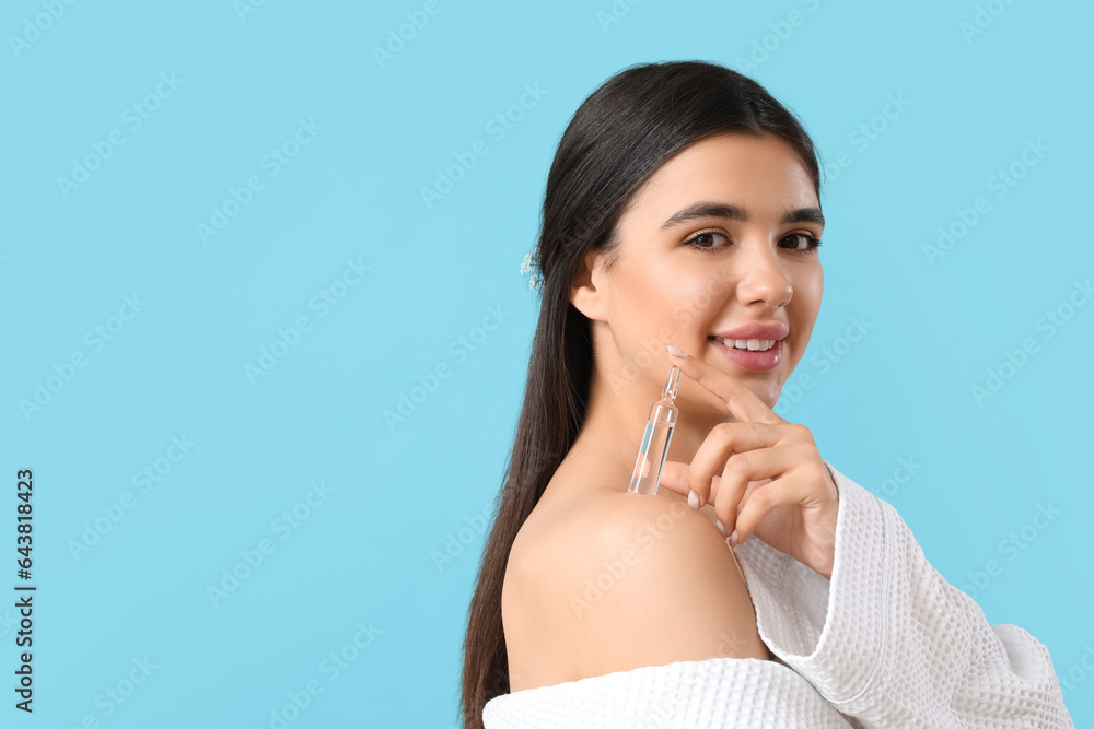 Beautiful young woman with ampule on blue background, closeup