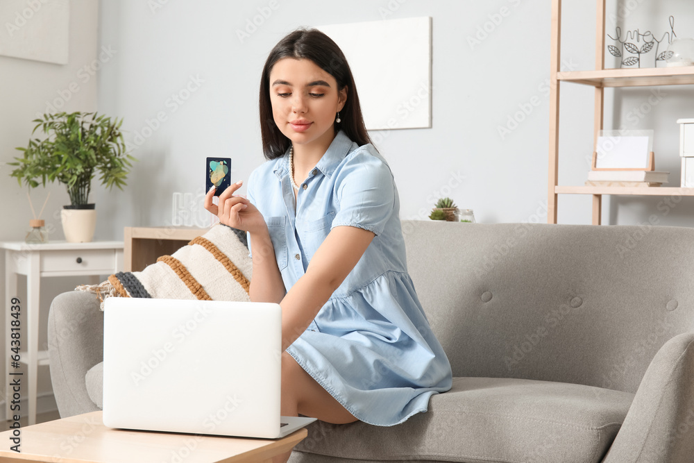 Young woman with credit card and laptop shopping online at home