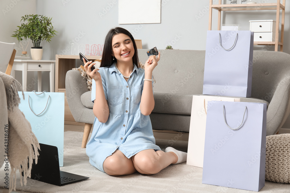 Young woman with credit card and mobile phone shopping online at home