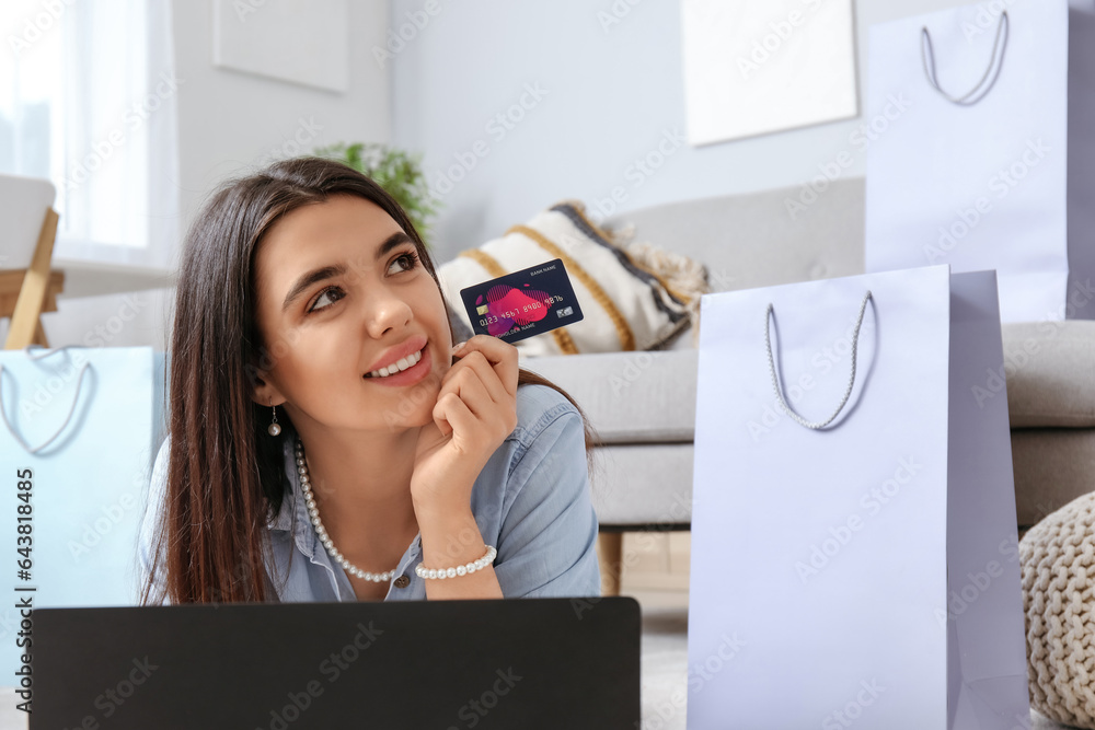 Young woman with credit card and laptop shopping online at home