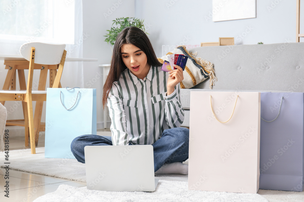 Young woman with credit cards and laptop shopping online at home