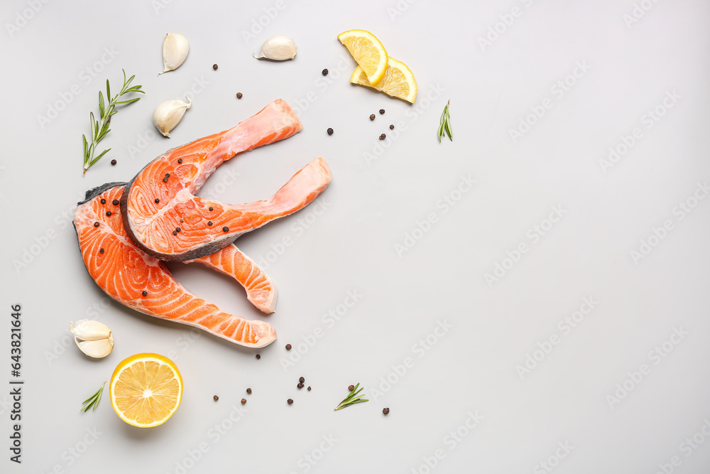 Raw salmon steaks and different spices on grey background