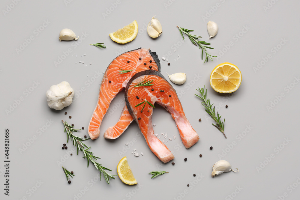 Raw salmon steaks and different spices on grey background