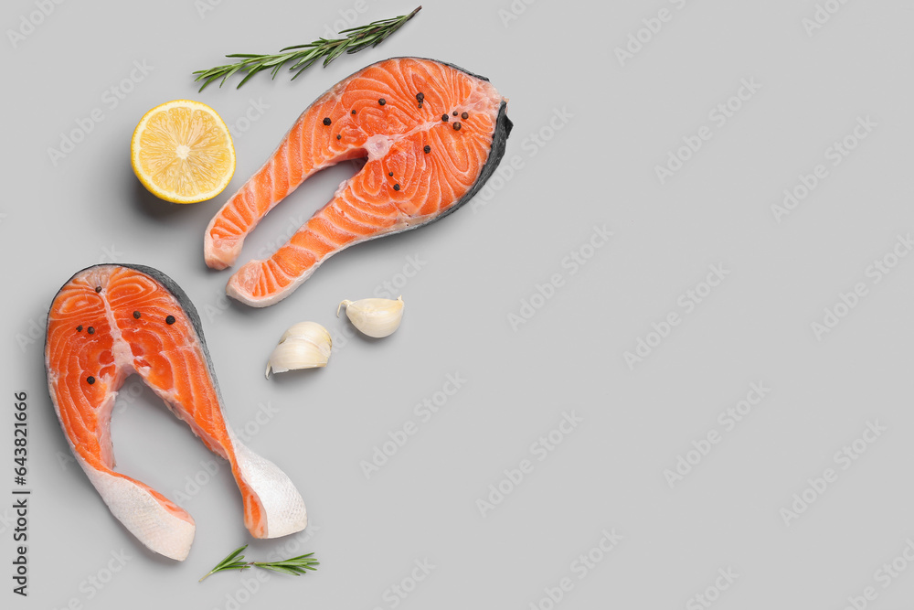 Raw salmon steaks and different spices on grey background