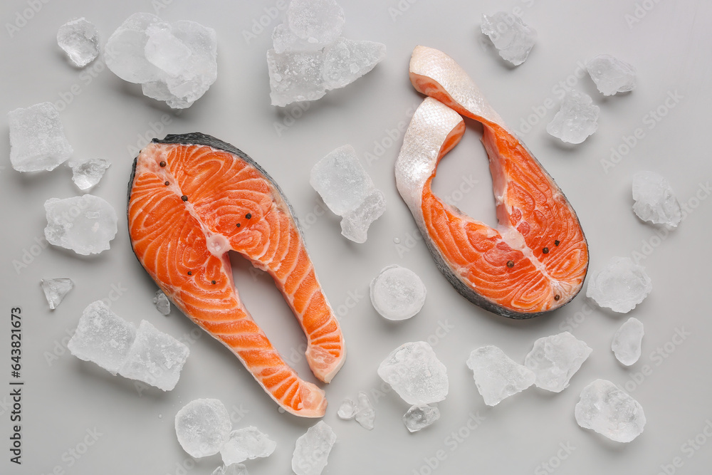 Raw salmon steaks with peppercorn and ice cubes on grey background