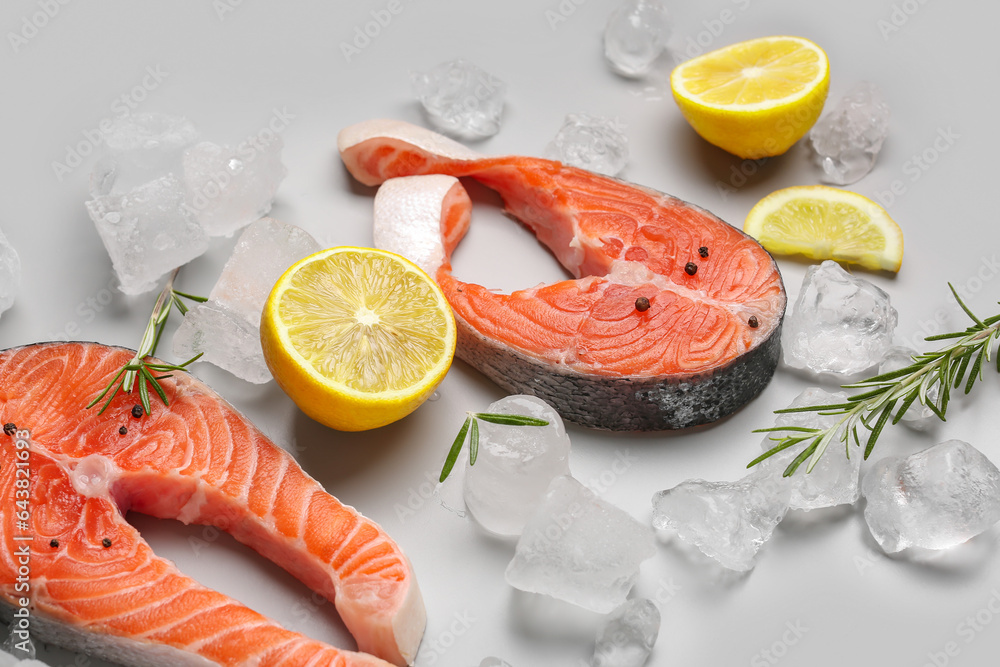 Raw salmon steaks with different spices and ice cubes on grey background