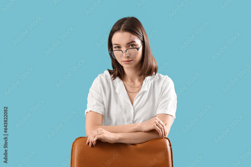 Young businesswoman with office chair on blue background